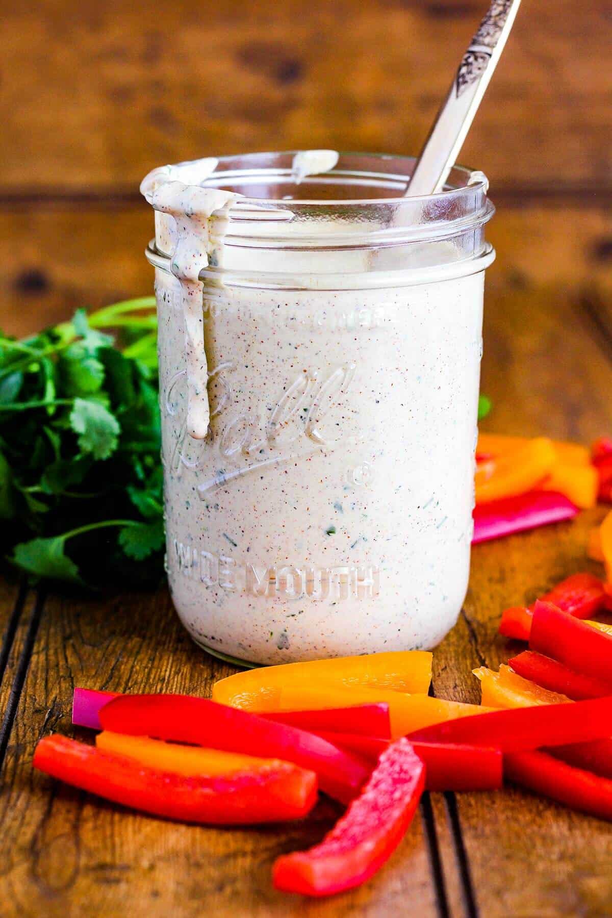 Jar with ranch dripping down the side with veggies.