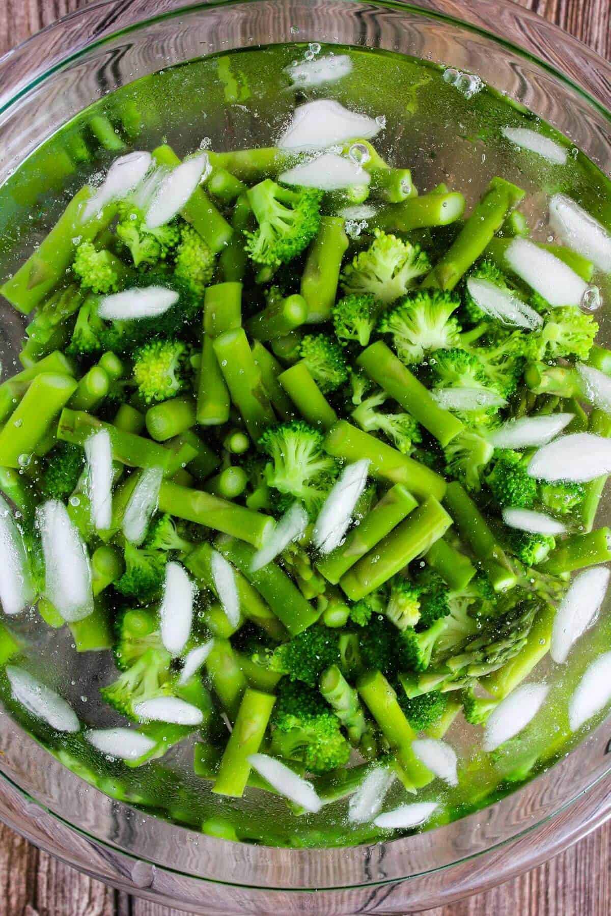 Broccoli and asparagus in a bowl of ice water.