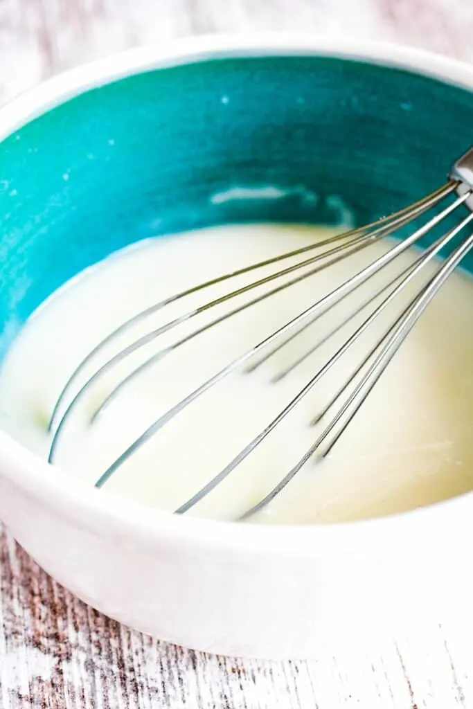 Vanilla lemon glaze in a bowl with a whisk.