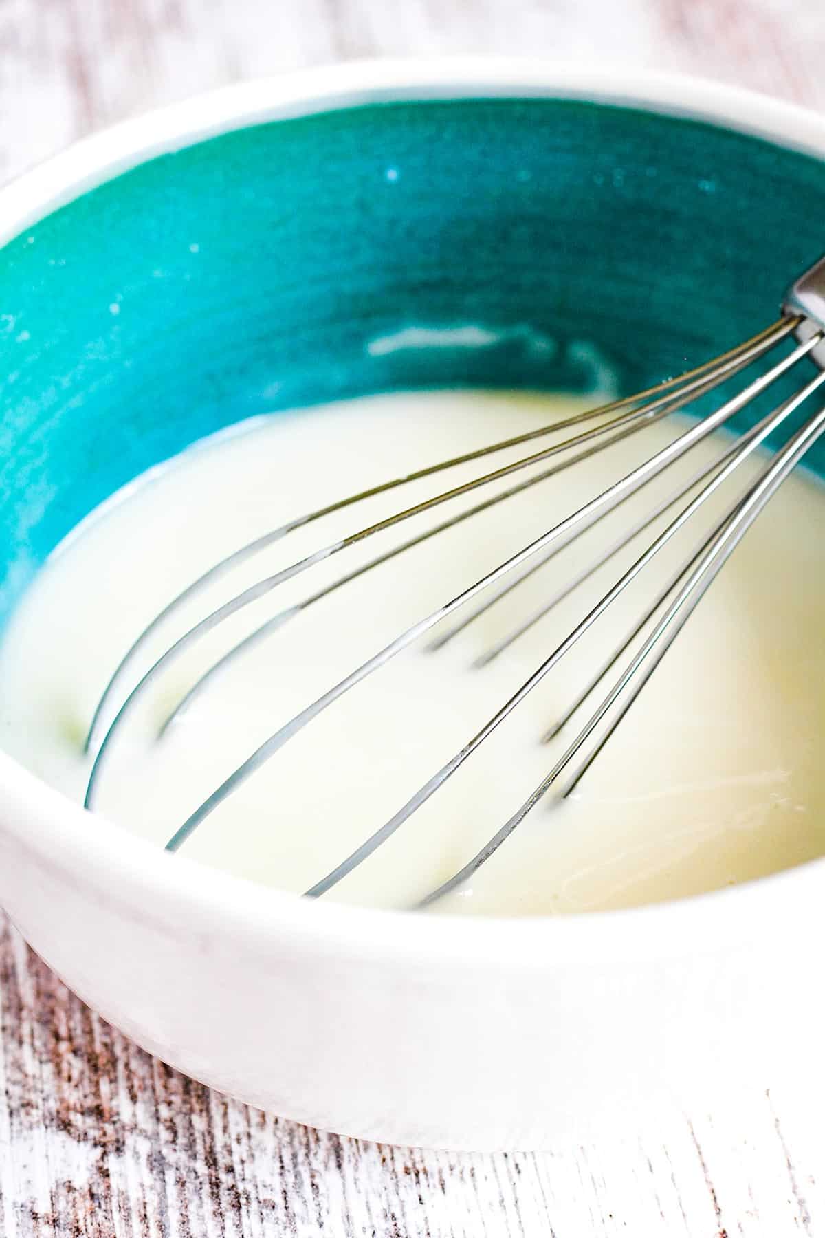 Vanilla lemon glaze in a bowl with a whisk.