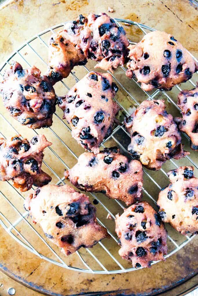 Fried blueberry fritters on a wire cooling rack.