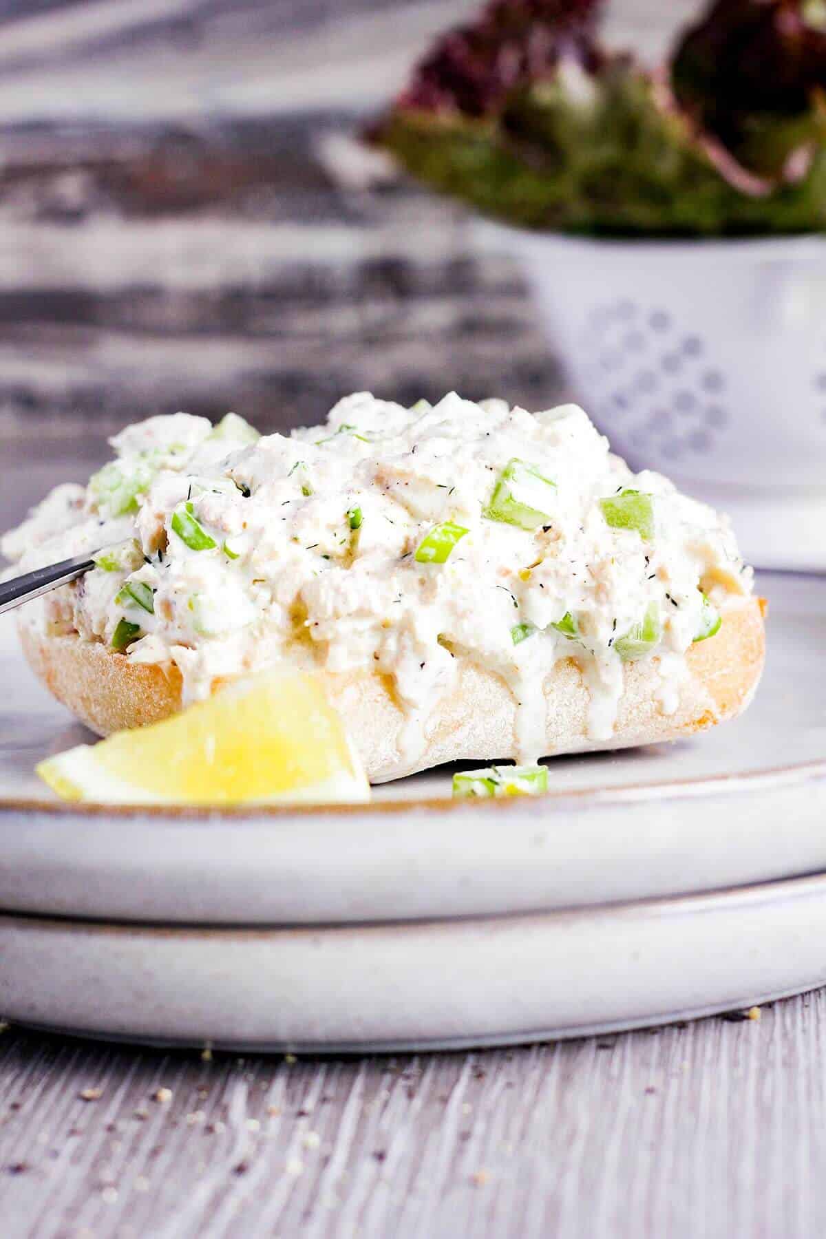 A slice of bread topped with dill tuna salad with lemon.