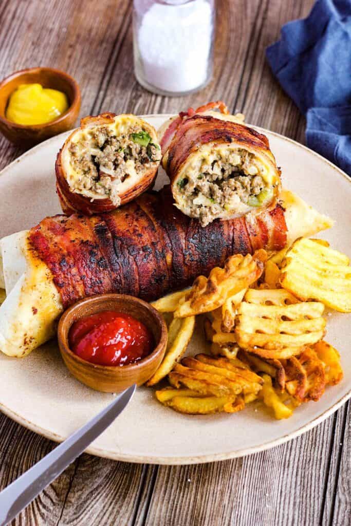 Cheeseburger burritos on a plate with fries and ketchup.