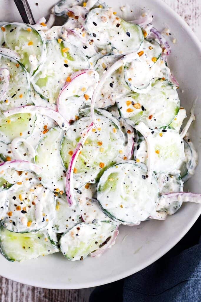 Bowl of creamy cucumber salad with onions.