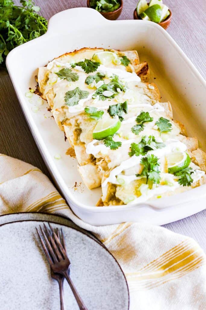 Pan of enchiladas with plates and forks.