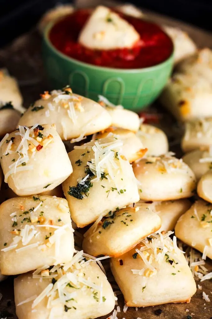 Pile of garlic bread bites with a bowl of marinara.