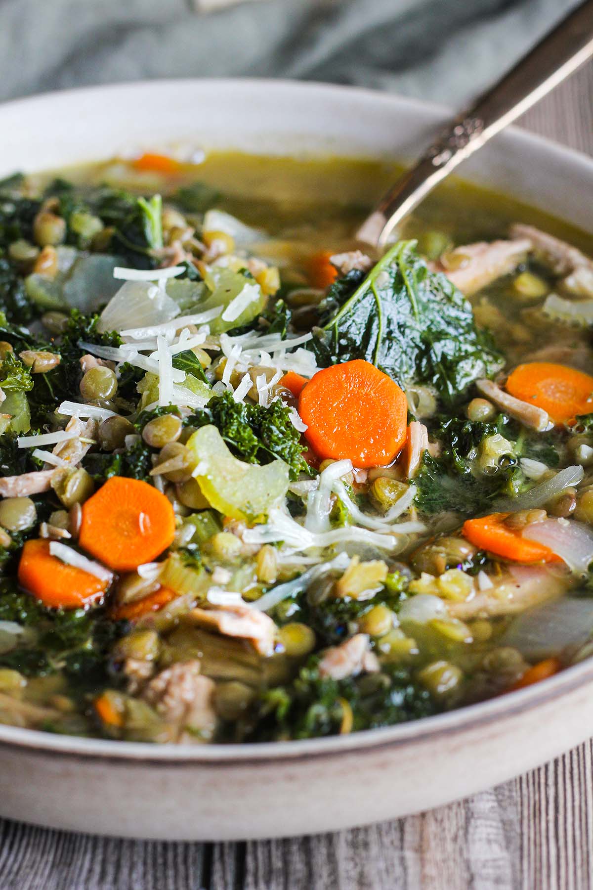 Close-up of bowl of lentil turkey soup with a spoon.
