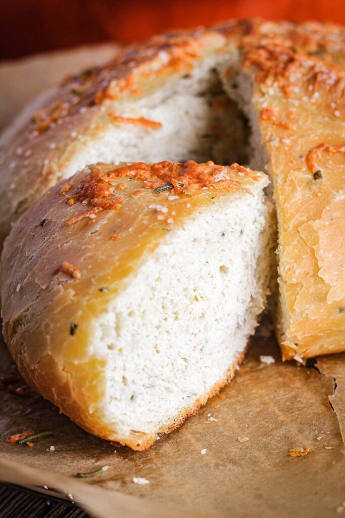 Close-up of slice of rosemary Parmesan bread aside the remainder of the loaf.