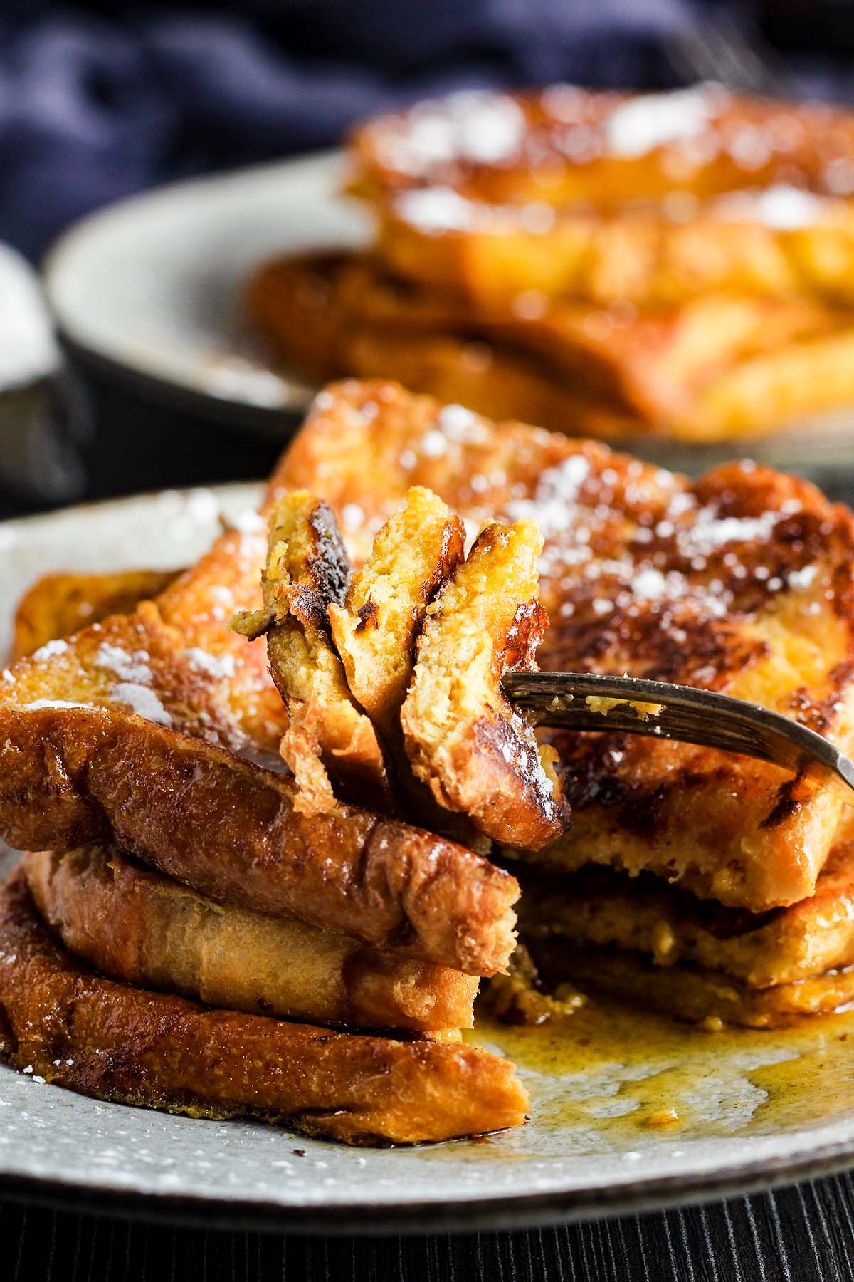 Close-up of stack of French toast with a piece cut out.
