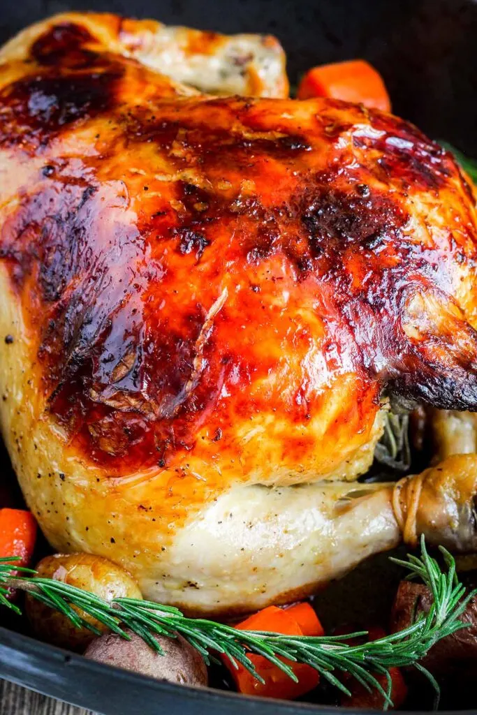 Close up of orange juice brined chicken with a rosemary sprig.