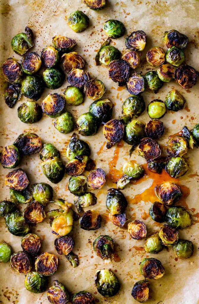 Sriracha honey Brussels sprouts on a baking sheet with splatter sauce.