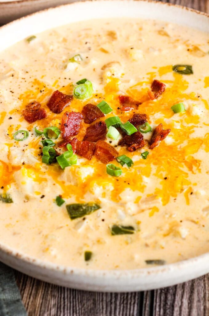 Bowl of cauliflower soup garnished with bacon bits and scallions.