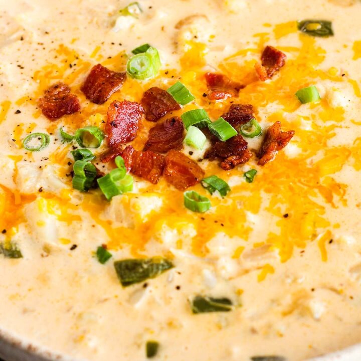 Bowl of cauliflower soup garnished with bacon bits and scallions.