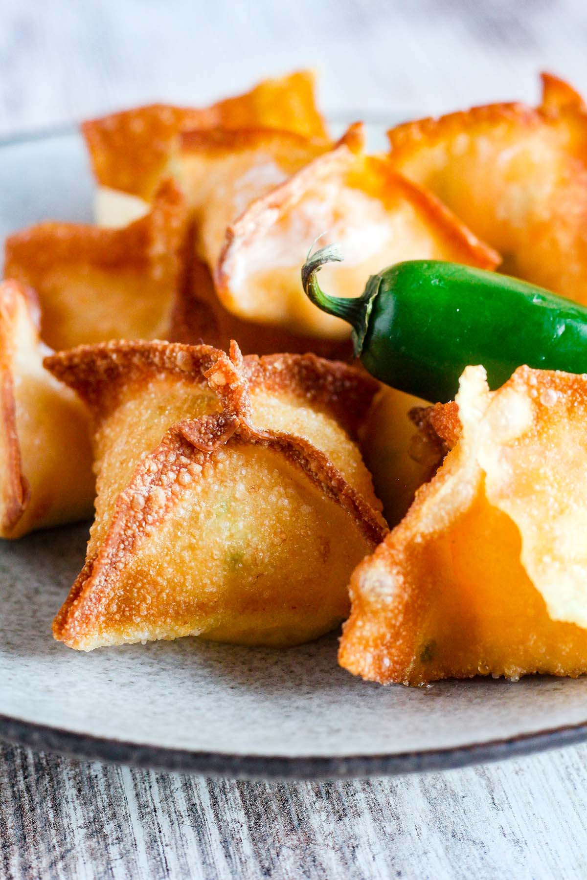 Close up of fried wonton poppers with a jalapeno