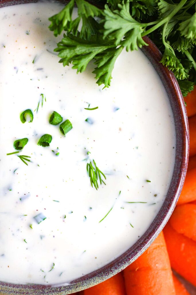 Close up of garlic ranch dip with carrots surrounding it