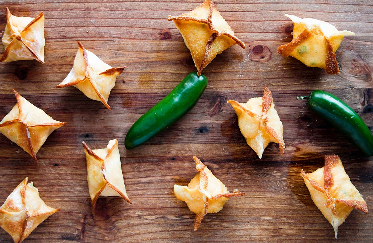 Five air fried wonton poppers next to five deep fried wonton poppers with two jalapenos