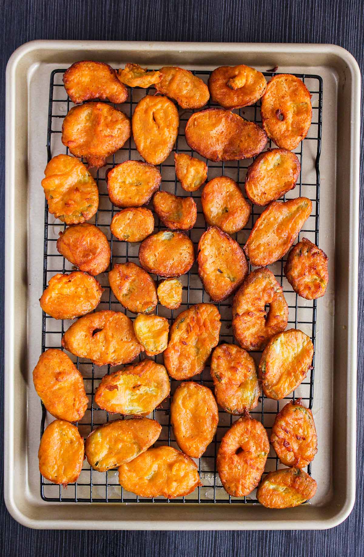 Fried pickles on a wire cooling rack atop a sheet pan