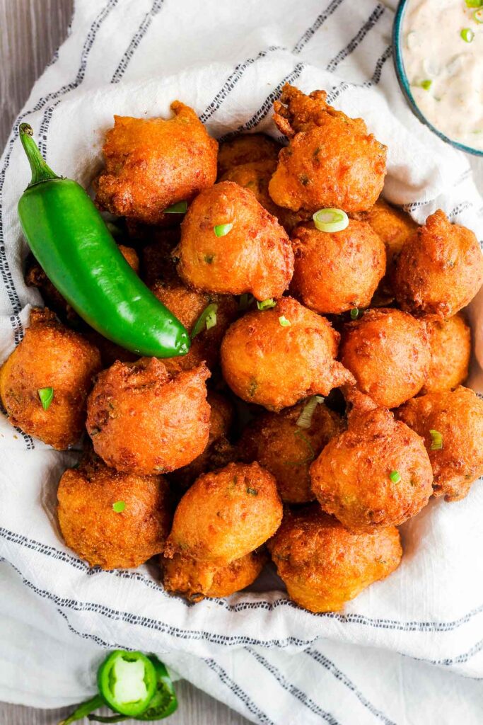 Stack of jalapeno hush puppies with a whole jalapeno