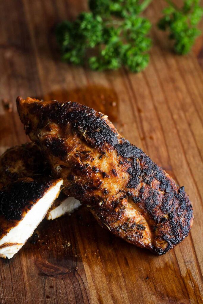 Close up of blackened chicken strip with parsley in background.