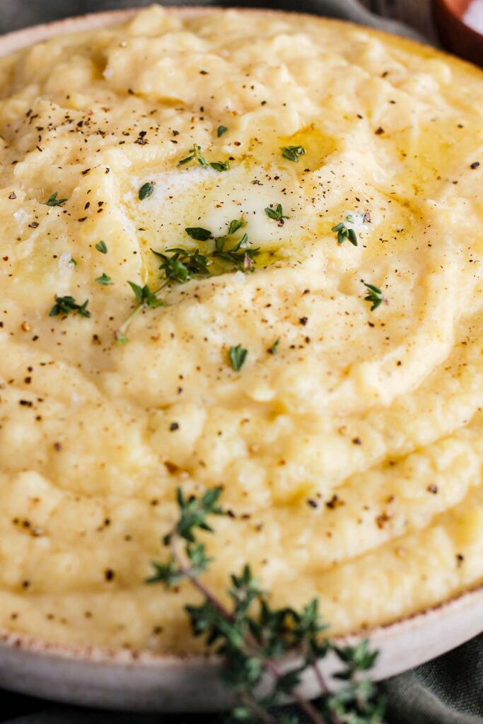 Close up of bowl of miso mashed potatoes garnished with black pepper, butter, and thyme.