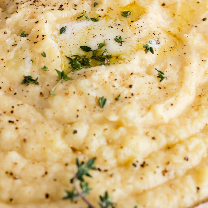 Close up of bowl of miso mashed potatoes garnished with black pepper, butter, and thyme.