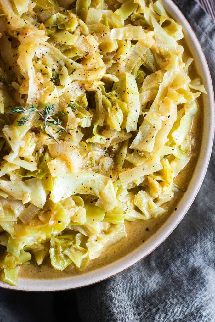 Bowl of mustard braised cabbage atop a green kitchen towel.