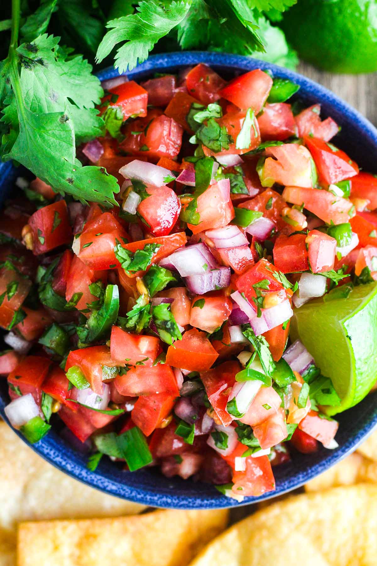 Bowl of salsa garnished with a lime wedge.