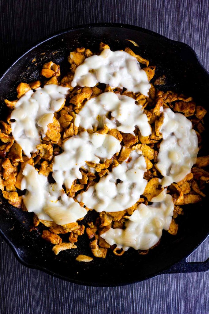 Buffalo chicken in a skillet topped with melted Provolone.