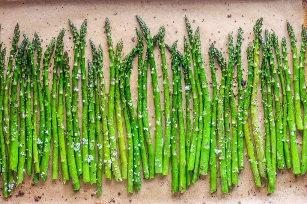 Close up of roasted asparagus on a baking sheet with truffle salt.