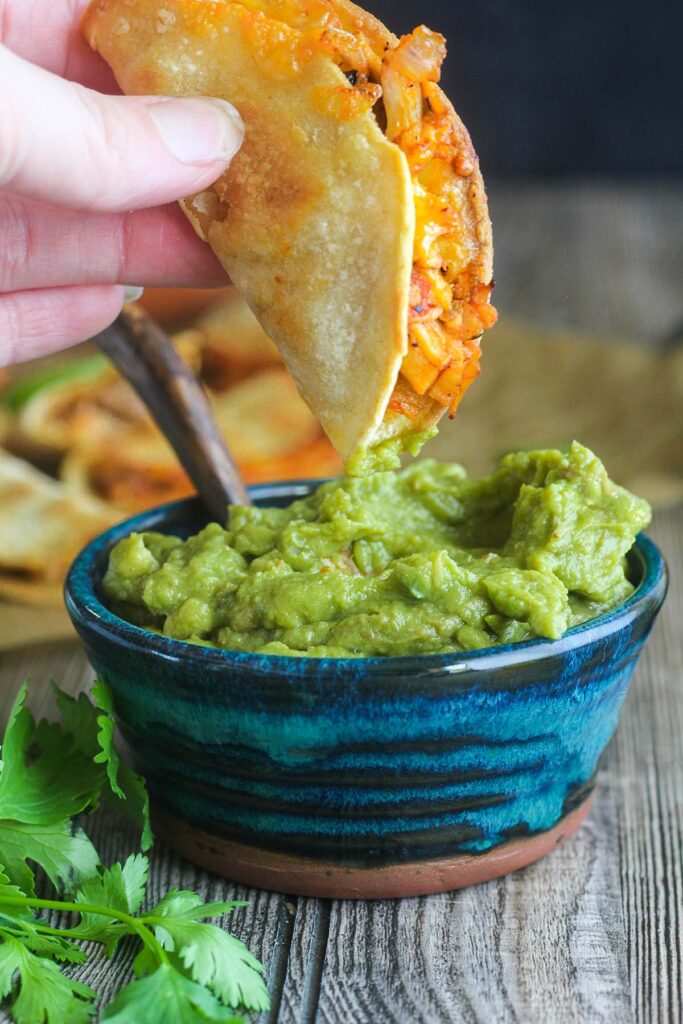 Mini air fryer taco being dipped in bowl of guacamole.