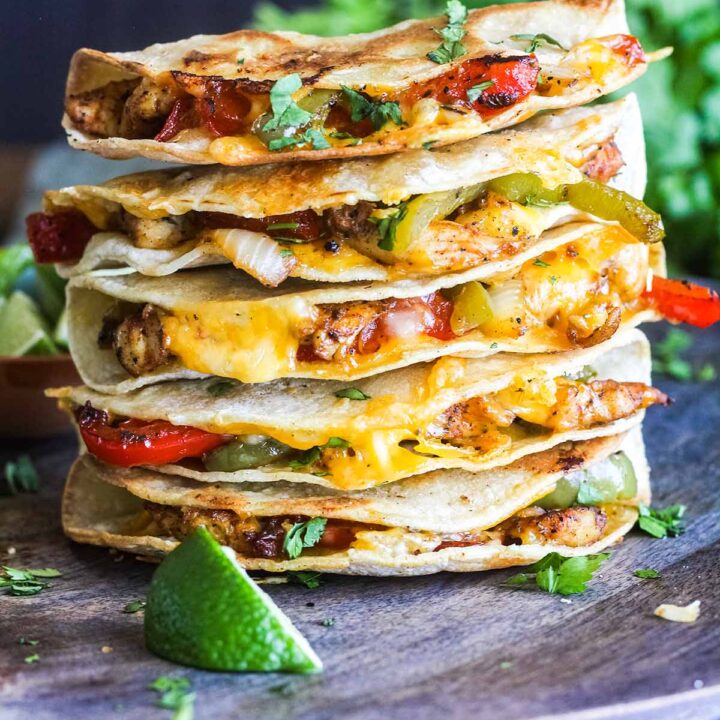 Stack of crispy chicken fajita tacos with a bowl of salsa and bunch of cilantro.