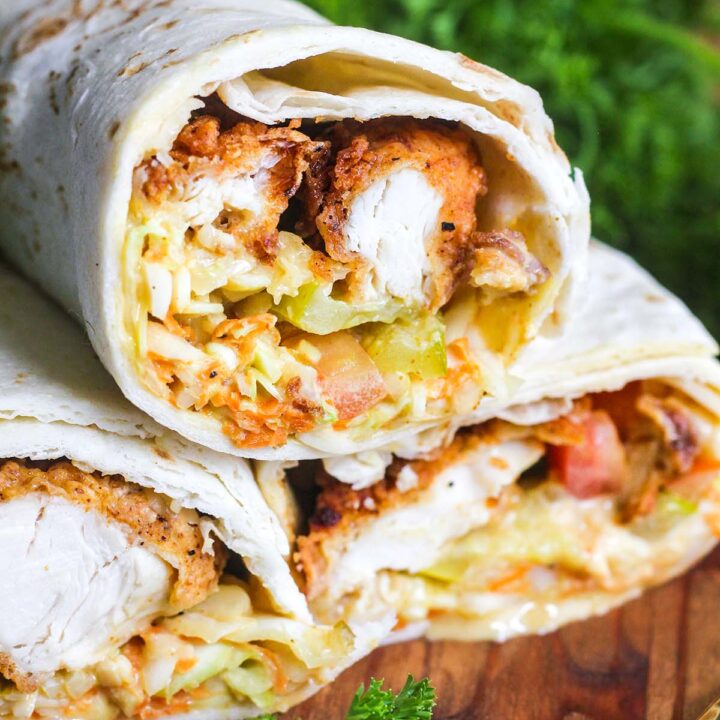 Stack of honey mustard chicken wraps surrounded by parsley and a spoon dripping with honey mustard.