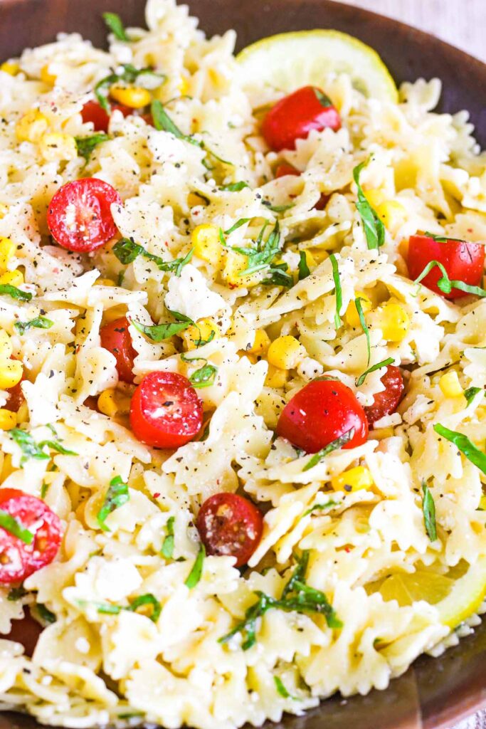 Close up of basil lemon pasta salad with corn and tomatoes.