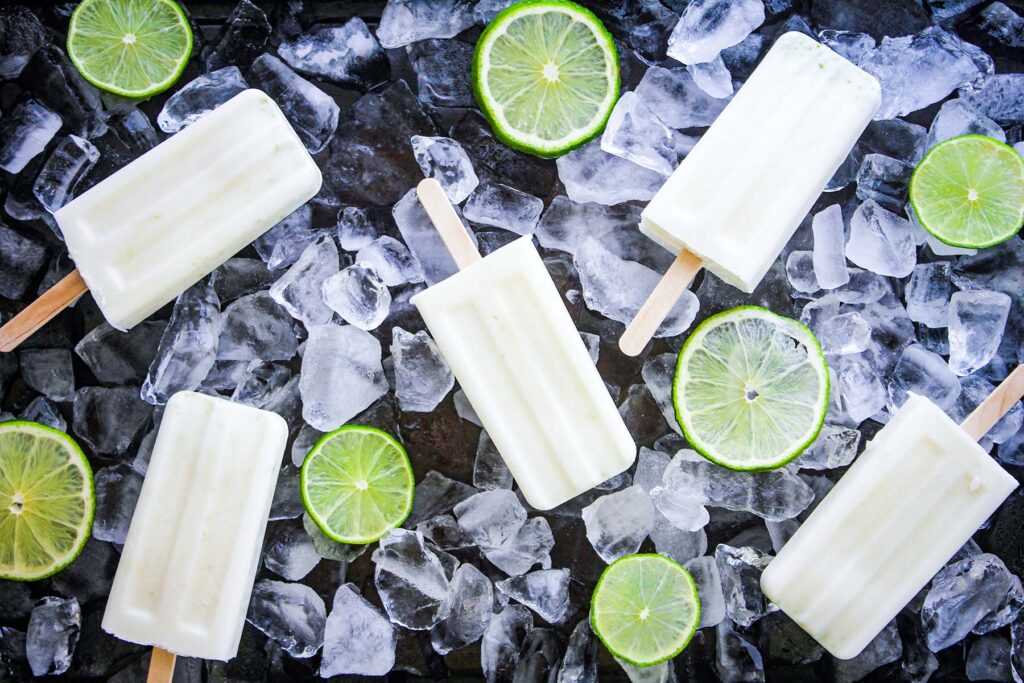 Coconut lime pops atop a bed of ice with sliced limes.