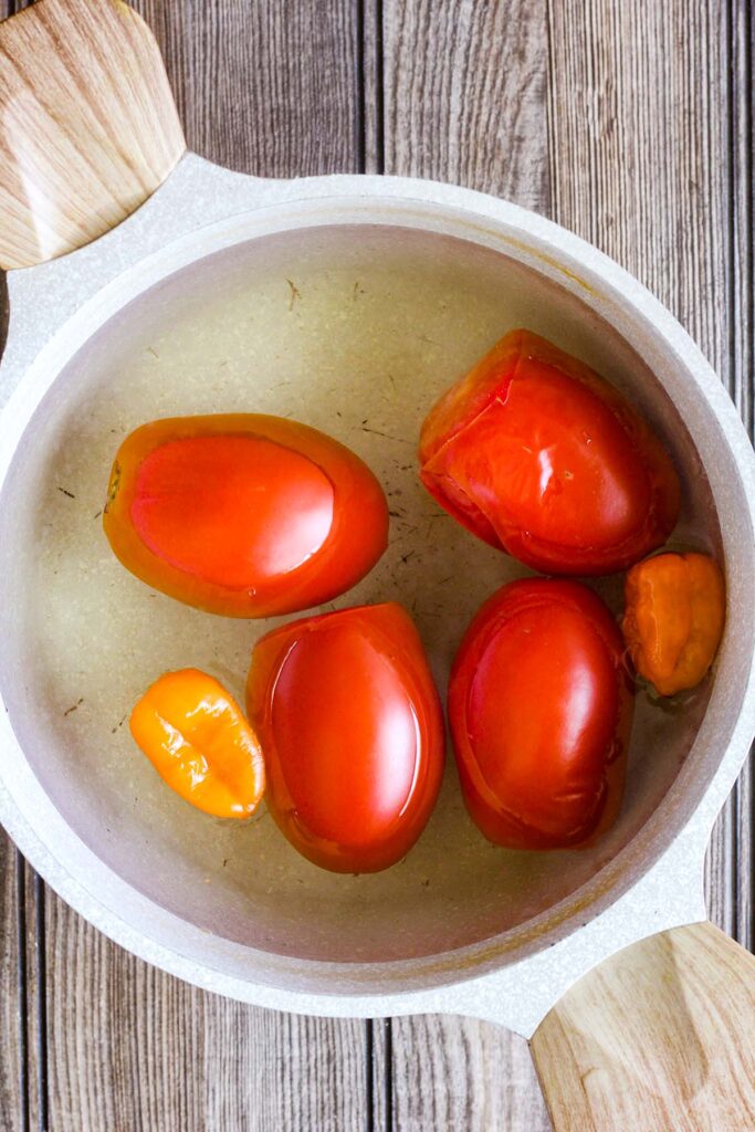 Tomatoes and habanero peppers in a pot of water.