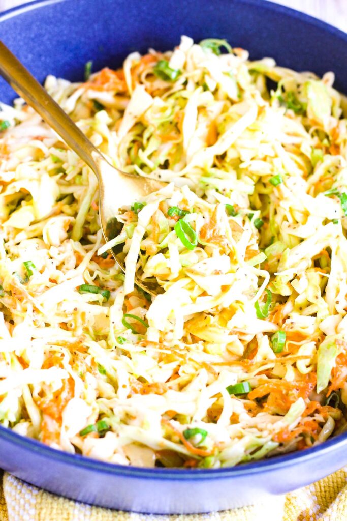 Close up of bowl of mustard slaw with a spoon.